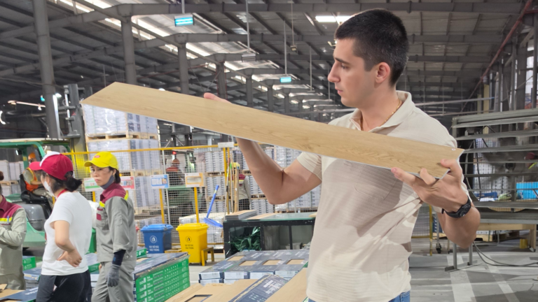 Nick Popović reviewing an SPC flooring plank during factory production in Vietnam